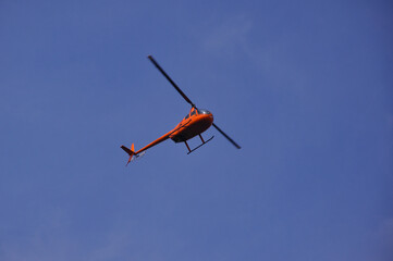 Fototapeta na wymiar Helicopter flies against the blue sky