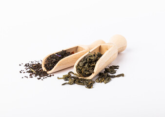 Green and black tea in slides and in a wooden spoon isolated on a white background. Dry tea leaves...