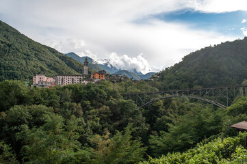 Fototapeta premium A small village in the Swiss mountains with an iron railway bridge over the valley.