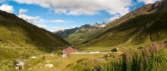 The Nufenenpass road leads through the valley between the high mountains of the Swiss Alps