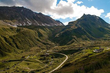The Nufenenpass road leads through the valley between the high mountains of the Swiss Alps