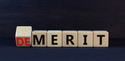 Demerit or merit symbol. Turned wooden cubes and changed the concept word Demerit to Merit. Beautiful black table black background. Business and demerit or merit concept. Copy space.