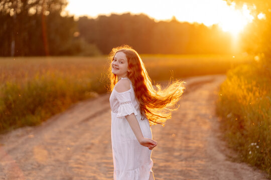 Curly-haired girl enjoying the sunset in the field.