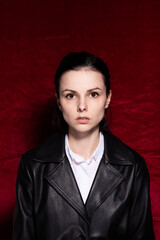 Woman in white shirt and black leather jacket on red velvet background