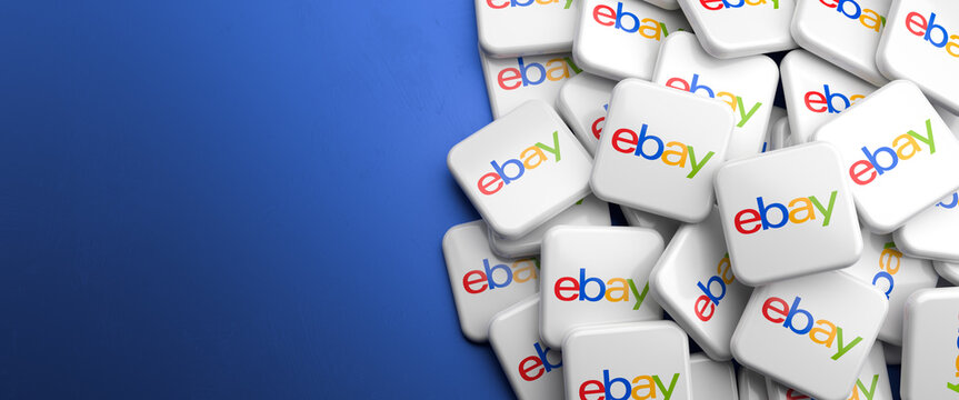 Logos of the ecommerce and auctioning company ebay on a heap on a table. Copy space and selective focus. Web banner format.