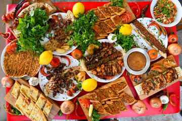 Traditional Turkish cuisine. Pizza, pita, pidesi, sucuk, hummus, kebab. Many dishes on the table. Serving dishes in restaurant. Background image. Top view, flat lay
