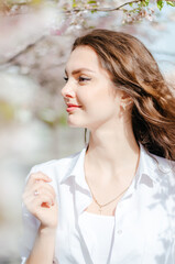 Obraz premium Girl in a white shirt near the sakura trees. Sakura blossoms. Spring.