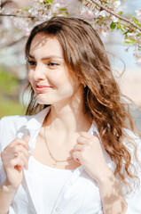 Girl in a white shirt near the sakura trees. Sakura blossoms. Spring.