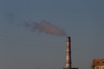 Pipes of an old factory throw clouds of poisonous white smoke into the sky polluting the...