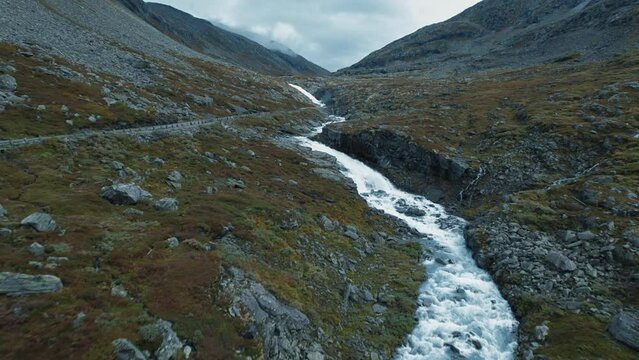Beautiful flying shot of aesthetic village countryside mountain road, river covered with moss, rocks. Scandinavian, nordic healthy traveling exploring outdoors culture. Dreamy, cinematic 4k footage