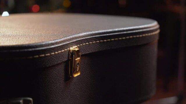 The guitarist closes the latch of the corrugation for the guitar in close-up. A case for a musical instrument. Opening guitar case