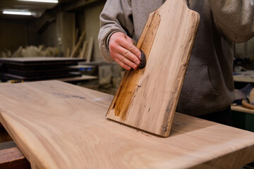 Closeup of Carpenter coating a wooden cutting board with protective flaxseed oil