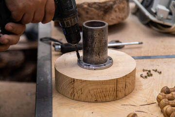Fototapeta na wymiar Closeup man tightening a screw to round wooden turning blanks