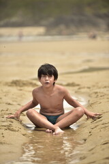 portrait of a child sit in the beach in summer wear
