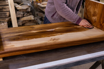 Carpenter coating a wooden table with protective flaxseed oil