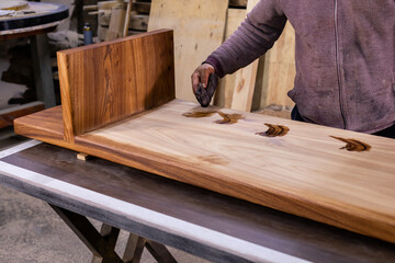 Carpenter coating a wooden table with protective flaxseed oil