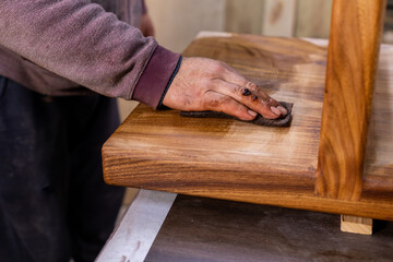Closeup of carpenter coating a wooden table with protective flaxseed oil