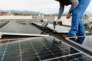 Man worker installing solar photovoltaic panel system using screwdriver. Alternative energy concept