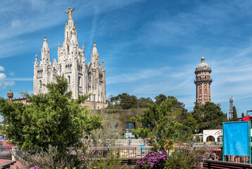 Tibidabo Cathedral in Barcelona, Spain. Temple of the Sacred Heart of Jesus at Mount Tibidabo. High tree tree and blue sky with cloud of summer day. Famous landmark in Catalonia, Espana.