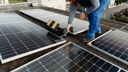 Technical engineer installing solar photovoltaic panel system using screwdriver. Alternative energy concept