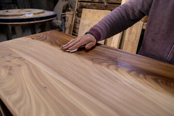 Closeup of carpenter coating a wooden table with protective flaxseed oil