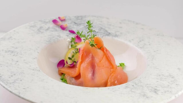 Close-up of sliced smoked salmon with lemon on a decorated plate.