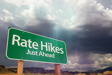 Rate Hikes Green Road Sign Over Dramatic Clouds and Sky.
