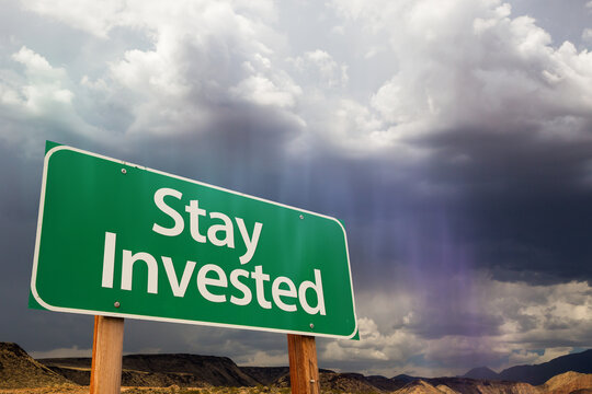 Stay Invested Green Road Sign Over Dramatic Clouds And Sky.