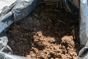 Spring cleaning on the balcony, woman replanting balcony flowers in pots, planting garden soil, garden soil for flowers, balcony decorated with flowers.