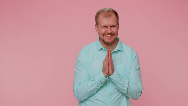 Sneaky cunning man with tricky face gesticulating and scheming evil plan, thinking over devious villain idea, cunning cheats, jokes and pranks. Young guy on pink studio wall background alone indoors
