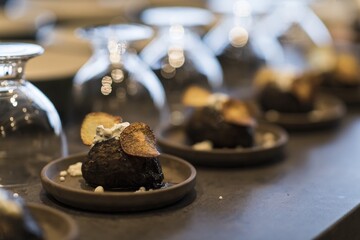 Preparing dinner. Potatoes in ashes, cream, truffles, chives, plate. Table, close-up, dining, background, lighting, people. Beautiful surroundings, adventure restaurant.