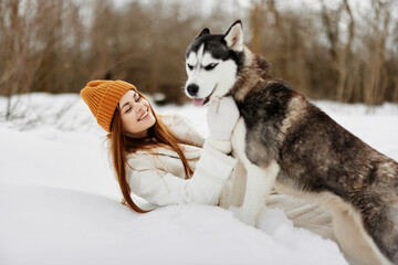 Happy young woman in the snow playing with a dog fun friendship fresh air