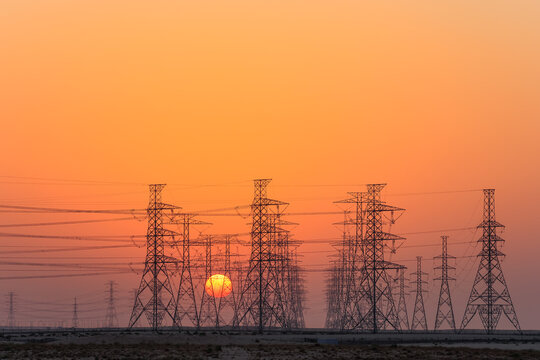 High-voltage power lines in Saudi Arabia (KSA) at sunset or sunrise. High voltage electric transmission tower. 
