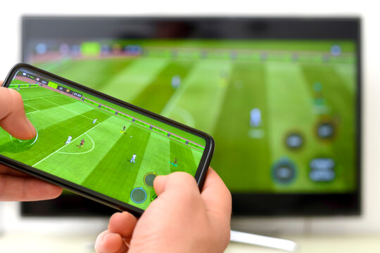 person playing soccer game on tv with smart mobile phone