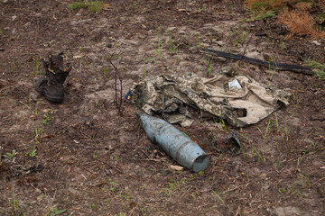 Burnt military uniform, shoes, artillery shell