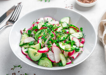 Fresh salad with radish and cucumber on a gray background. Side view, close-up. Healthy food.