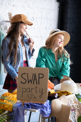 Happy women at swap party. Choose casual clothes, shoes, hats, bags, jewellery. Idea of exchange your old wardrobe for new. Eco friendly cloth concept. Zero waste shopping, reduce and reuse, donation