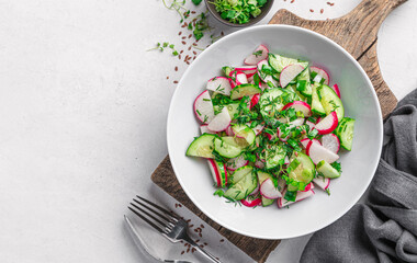 Salad with radish, cucumber, micro greens and flax seeds on a light background. Diet salad. View from above.