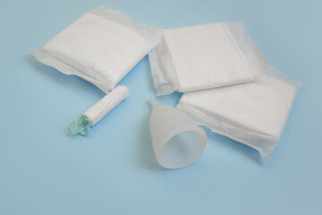 Pad, menstrual cup, tampon on a blue background. The view is flat. Concept of critical days, menstruation