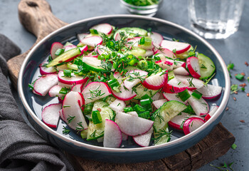 Salad with radish, cucumber and fresh herbs on a dark blue background. Side view, close-up.