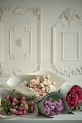 A several bouquets of flowers of different colors on a beige background with bas-relief
