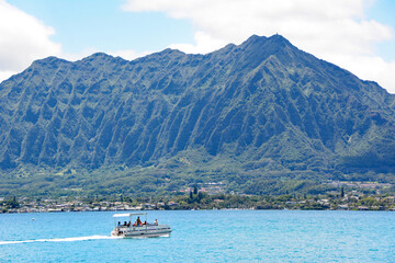 Fototapeta na wymiar Pontoon boat in Kaneohe Bay with mountains in background on the windward side of Oahu, Hawaii near Kaneohe Marine Corps Base