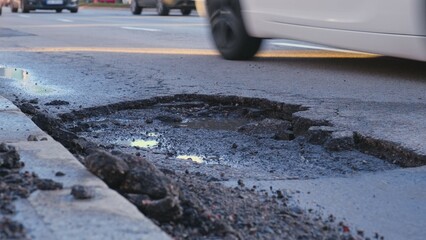 Vehicles Driving Over Large Erosion Damage Hole in City Street Asphalt after Severe Weather and...
