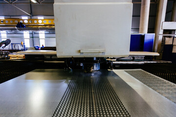 CNC punching and nibbling machine and perforated steel sheet, close up
