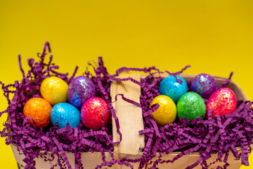 Easter composition from a basket and colored eggs prepared for the holiday on a yellow background
