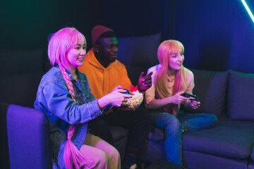 Modern entertainment concept. Three interracial young adults spending leisure time in gaming cafe...