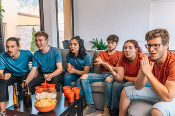 happy friends watching a football event on TV, one of them unexpectedly changes the channel, making the others angry.