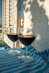 Drinking of red wine on outdoor terrace with view on old fisherman's harbour with colourful boats...