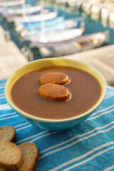 Homemade fish soup with croutons served with view on colorful fisherman's boats in harbour of Cassis, Privence, France.