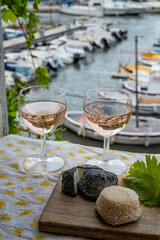 Rose wine in glasses served with goat cheeses on outdoor terrace with view on old fisherman's...